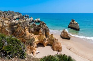Un paysage côtier caractérisé par des formations rocheuses et une plage de sable.