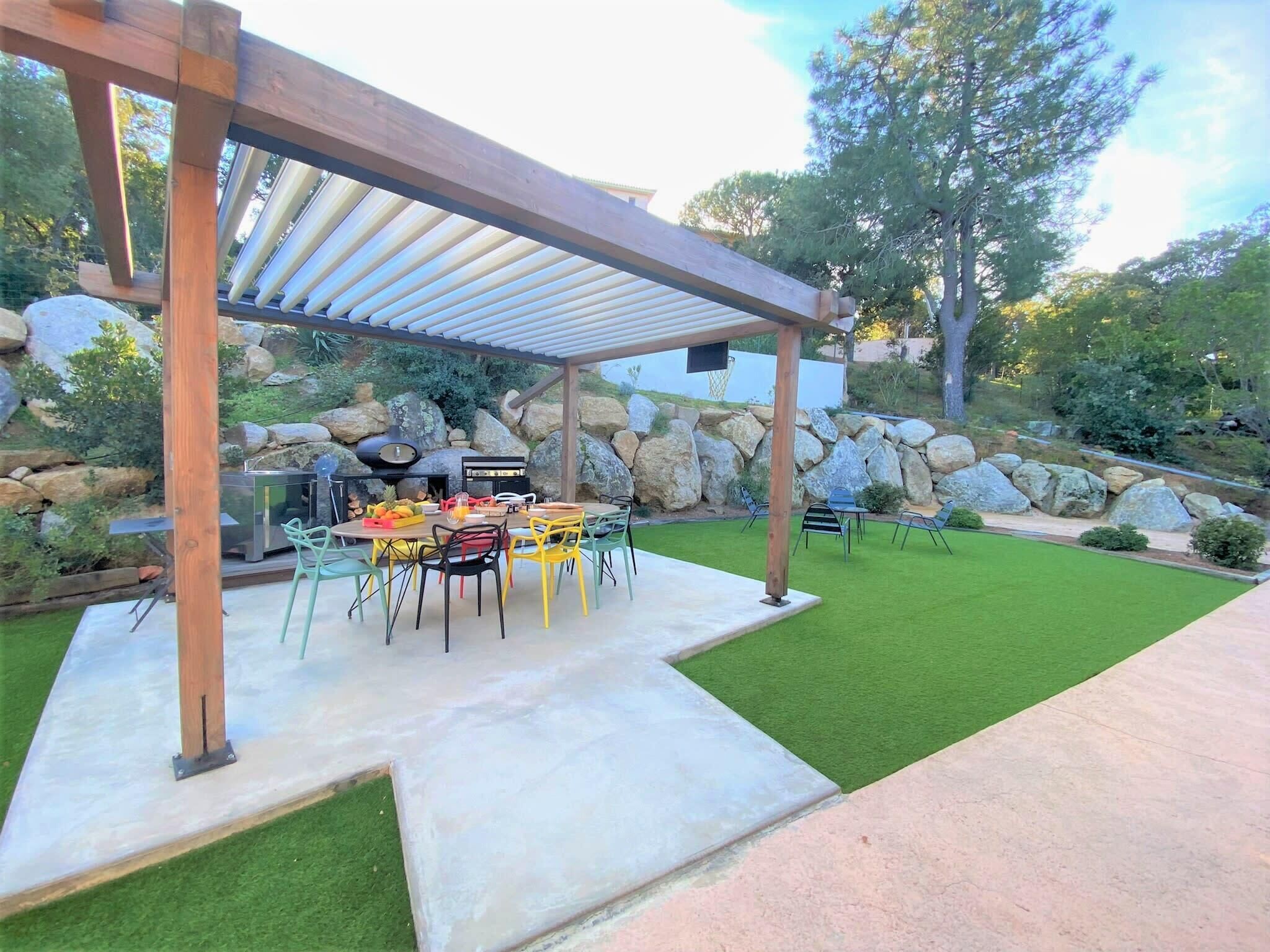 Un patio exterior con una pérgola, una parrilla y una mesa de comedor con sillas.