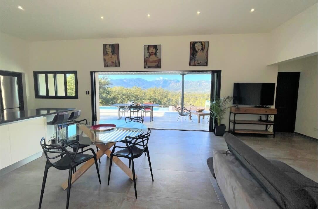 Una sala de estar moderna con comedor, un televisor grande y vistas a la montaña.
