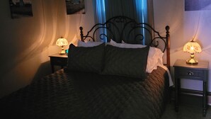 Ein Schlafzimmer mit einem Bett, zwei Nachttischen mit Lampen, einem Deckenventilator und Wandbildern.