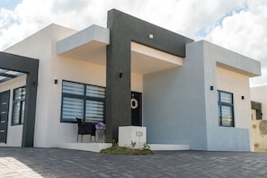 Un bâtiment moderne doté d’un toit plat, de grandes fenêtres et d’une plaque numérotée « 101 » à l’entrée.