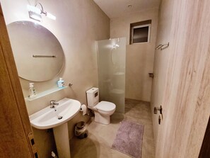 Un baño con lavamanos, inodoro y ducha con mampara de vidrio.