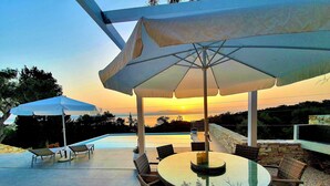 Eine Terrasse mit Pool, Gartenmöbeln und Sonnenschirmen.