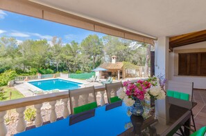 A balcony with a view of a swimming pool, outdoor furniture, and a table with a vase of flowers. - YourHouse Can Marques (Palma)