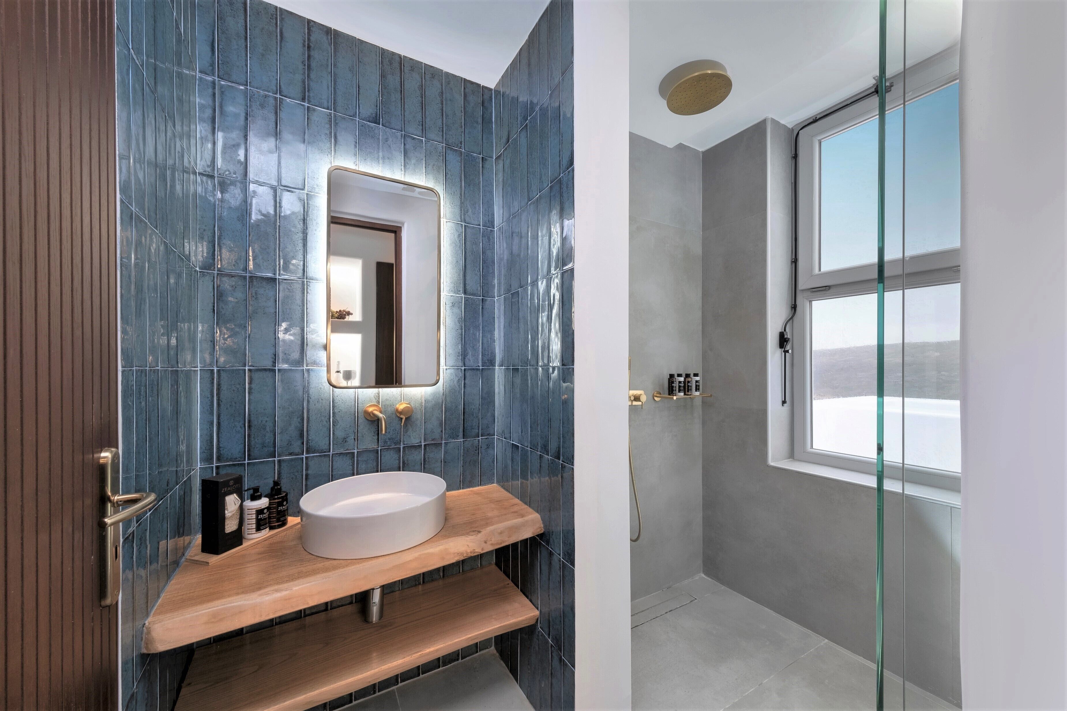 A modern bathroom with a large mirror, a wooden vanity, and a glass shower enclosure.