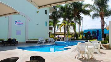 A hotel pool area with lounge chairs, a sign for 'Hotel Splash Inn,' and a mural on the building.