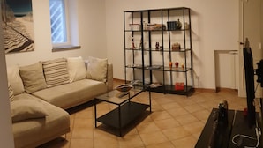 A living room with a sofa, a coffee table, a bookshelf, and a television.
