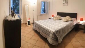 A bedroom with a bed, bedside tables, a dresser, a radiator, and a window.