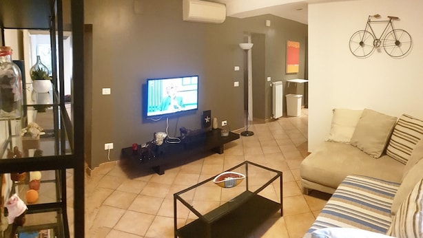 A living room with a television, a sofa, a coffee table, and a wall-mounted bicycle decoration.