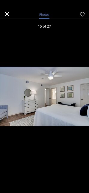 Quarto com cama, penteadeira, espelho e ventoinha no teto.