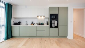 A modern kitchen with light green cabinets, a built-in stove, and a refrigerator. - Watford Cassio Luxury - Modernview Serviced Accommodation (Watford)
