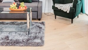 A modern living room with a grey sofa, a green armchair, a coffee table with fruit, and a potted plant. - Watford Cassio Luxury - Modernview Serviced Accommodation (Watford)