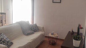 A cozy room with a bed, a small table, a potted plant, and a framed picture on the wall. - Apartment routes of the torcal (Villanueva de la Concepción)