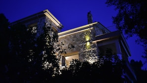 Ein Steinhof mit Balkon und einem beleuchteten Fenster im Dämmerlicht.