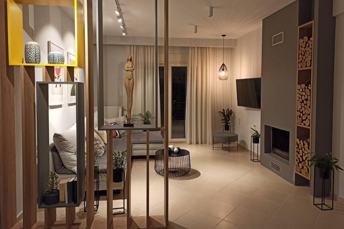 A modern living room with a sofa, a coffee table, a fireplace, and a TV mounted on the wall.