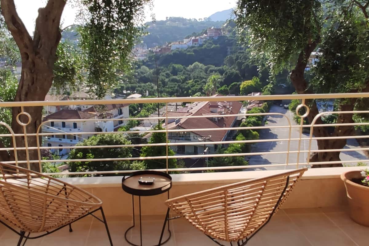 A balcony with two wicker chairs, a small round table, and potted plants.