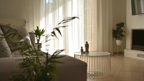 Ein modernes Wohnzimmer mit einer Couch, einem runden Couchtisch und zwei Zimmerpflanzen.