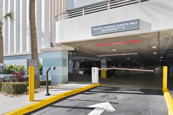 A private parking entrance with a clearance sign of 7'-4", a gated entrance, and a yellow curb.