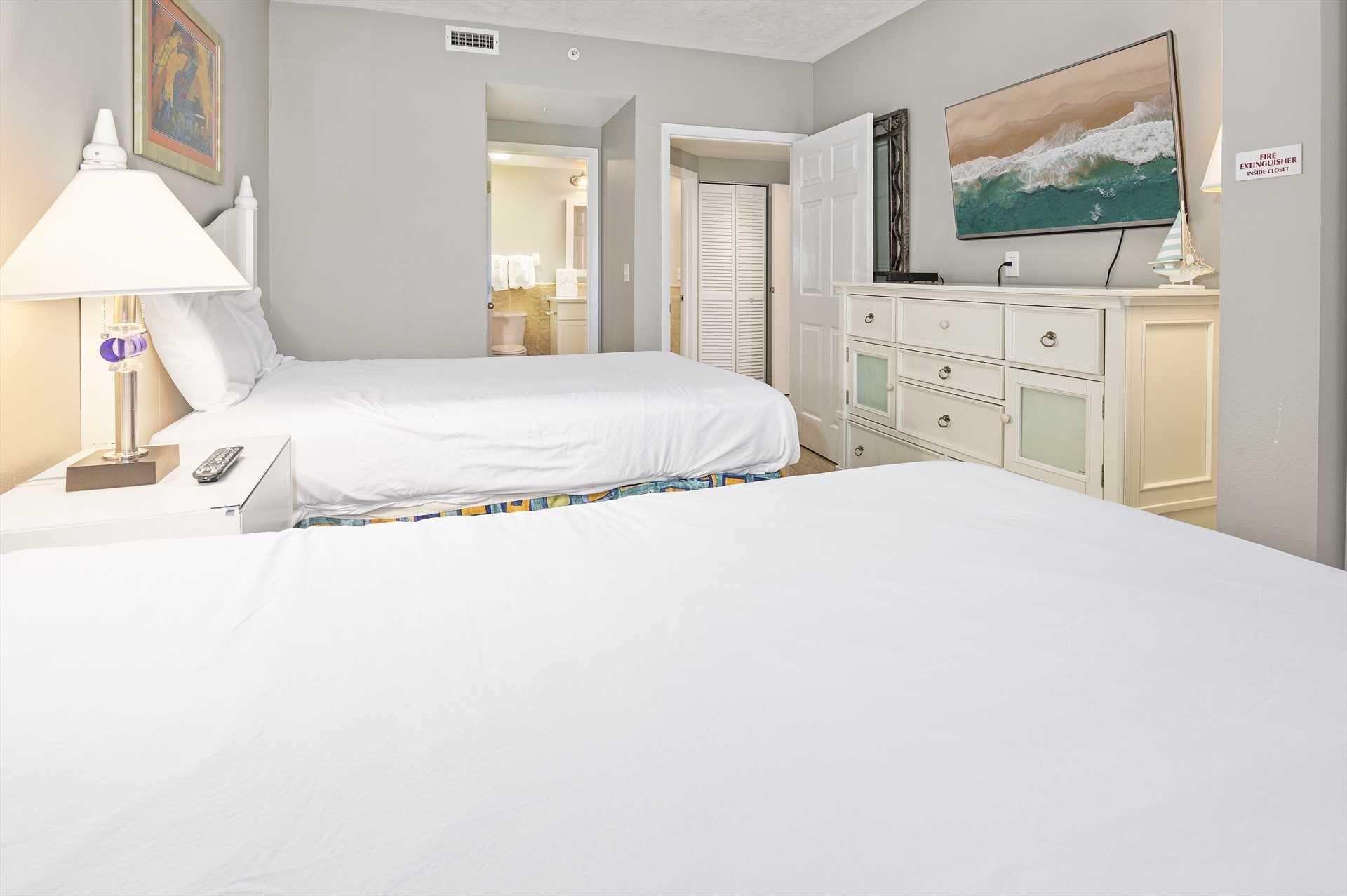 Une chambre d’hôtel avec deux lits, une télévision, une commode et un tableau au mur.