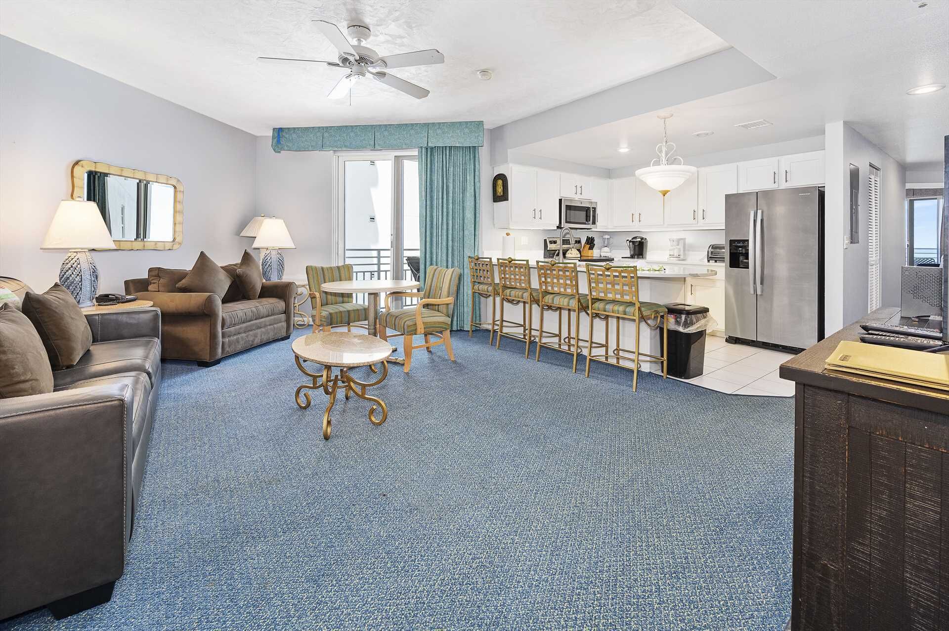 Une chambre d’hôtel dotée d’un coin salon, d’un espace repas et d’une kitchenette.