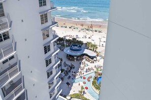 A hotel with a pool area, beach view, and a circular water feature.