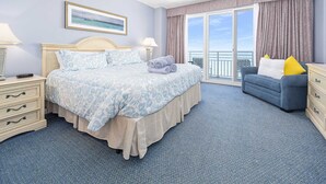 A bedroom with a bed, a nightstand, a dresser, a window with curtains, a ceiling fan, and a painting on the wall. - Luxury 12th Floor 2 BR Condo Direct Oceanfront Wyndham Ocean Walk Resort Daytona Beach | 1201 (Daytona Beach)