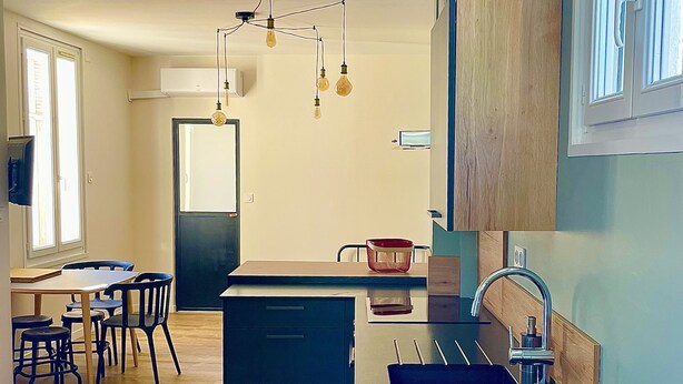 A modern kitchen with a central island, a dining area with chairs, and a built-in oven. - T3 5min from the beaches and creeks, FREE secure parking ! (La Ciotat)