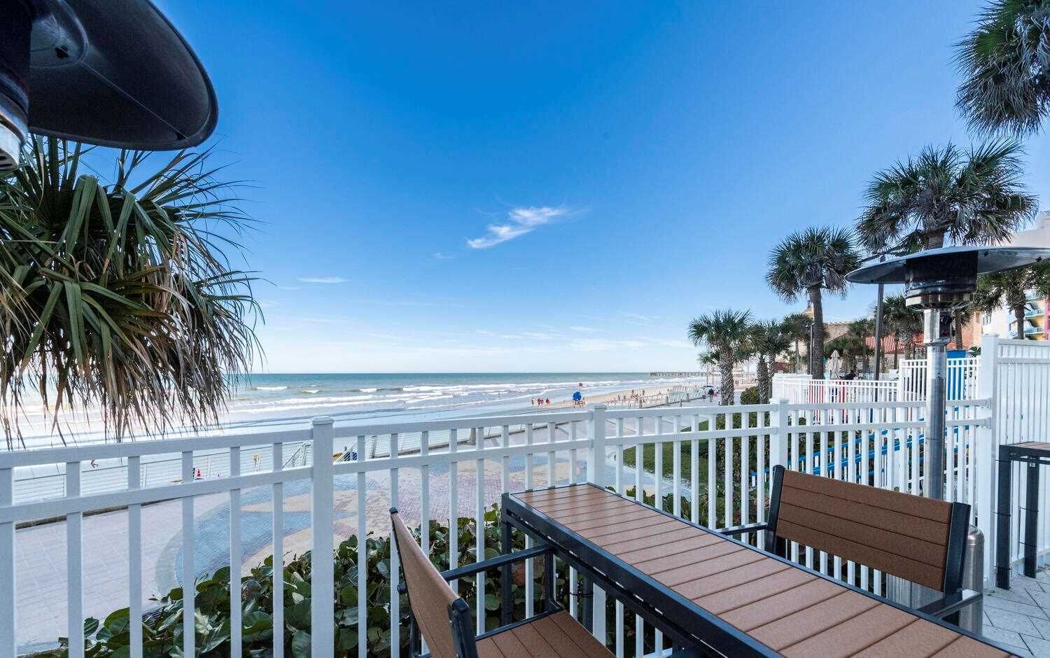 Een balkon met uitzicht op het strand, witte leuningen en een bankje.