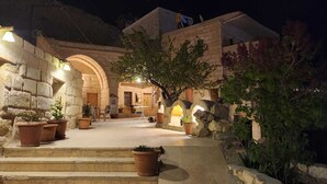 A stone building with a courtyard, potted plants, and outdoor seating. - Dede Cave Hotel (Ürgüp)