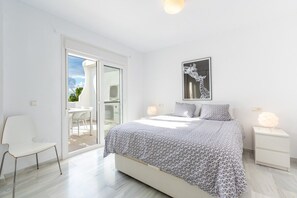 A bedroom with a bed, a chair, a nightstand, and a wall-mounted artwork. - Jardines de Calahonda III | Welcoming Apartment with Sea Views & Terrace (Mijas Costa)