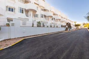 Un immeuble à plusieurs étages doté de balcons, une route pavée et un ciel dégagé.