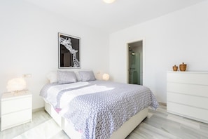 Une chambre à coucher comprenant un lit, des tables de chevet, une commode, une œuvre d’art accrochée au mur et une coiffeuse.