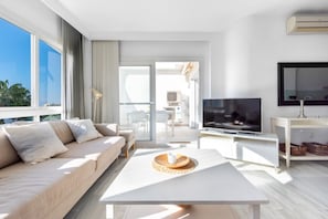 Un salon moderne avec un canapé, une table basse, un téléviseur et un balcon offrant une vue agréable.