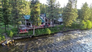 A lodge with a deck overlooking a river, surrounded by dense forest. - 40-acre haven on the banks of the Fall River (Ashton)