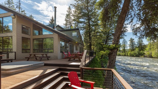A wooden deck with a red Adirondack chair, a wooden table, and a bench. - 40-acre haven on the banks of the Fall River (Ashton)