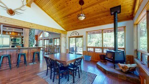 A spacious wooden interior with a dining area, kitchen, and a large fireplace. - 40-acre haven on the banks of the Fall River (Ashton)