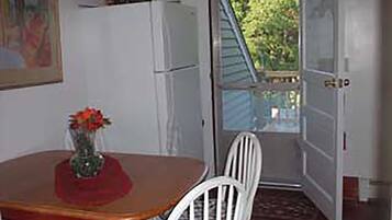 Une pièce comprenant une table à manger, des chaises, un réfrigérateur et une porte donnant sur l’extérieur.