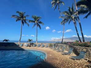 Relax by the pool with a clear view of the ocean and distant mountains.