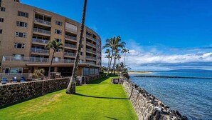 Ein Hotel am Strand mit mehreren Balkonen, einem gepflegten Rasen und Blick auf den Ozean.