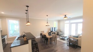 Una cocina moderna con una isla central, comedor con sillas y zona de estar con sofá y mesa de centro.