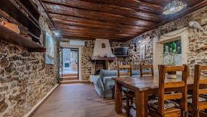 A rustic interior with stone walls, wooden furniture, and a fireplace.