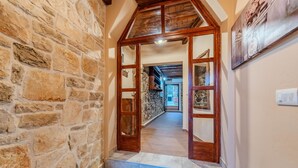 A stone-walled hallway with a wooden door leading to a room.