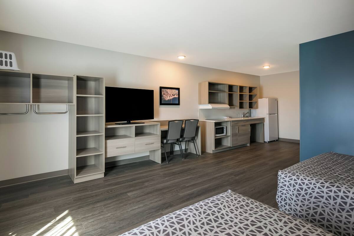 A modern, compact living space with a kitchenette, a flat-screen TV, and a dining area.