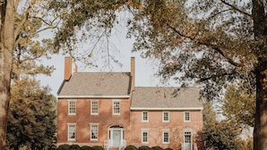 A two-story brick building with a symmetrical facade, a central entrance, and a well-maintained lawn. - Family Retreat at Lansdowne Manor (Centreville)