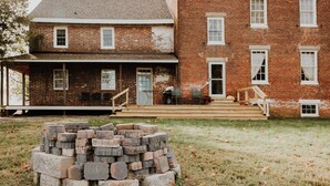 A two-story brick building with a front porch and a stack of bricks in the foreground. - Family Retreat at Lansdowne Manor (Centreville)