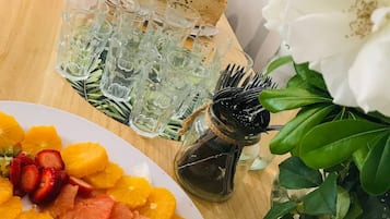 A wooden table with a plate of fruit, a bottle of sauce, and a glass pitcher.