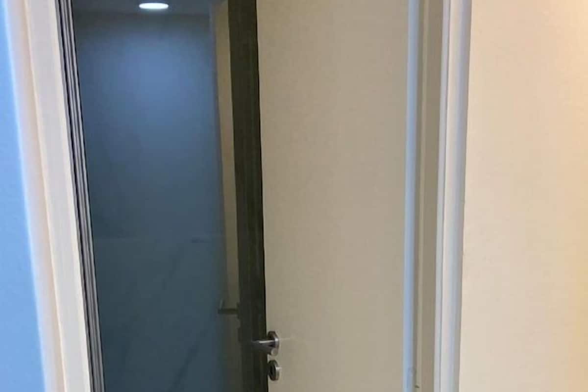 Un pasillo estrecho con una puerta de cristal que da a una habitación.