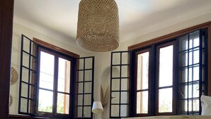 Una habitación con piso de madera, un sofá, una mesa con una cesta y una lámpara colgante.