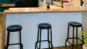 Une cuisine moderne dotée d’un îlot central, de tabourets de bar, de luminaires suspendus et offrant une vue sur la ville grâce à de grandes fenêtres.