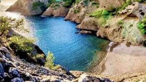 Un paysage côtier caractérisé par des falaises rocheuses et une eau d’un bleu limpide.
